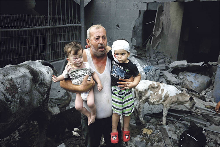 Refugiado palestino con sus nietos heridos en el campamento de Nuseirat (Gaza) | UNRWA / CC BY-SA 4.0