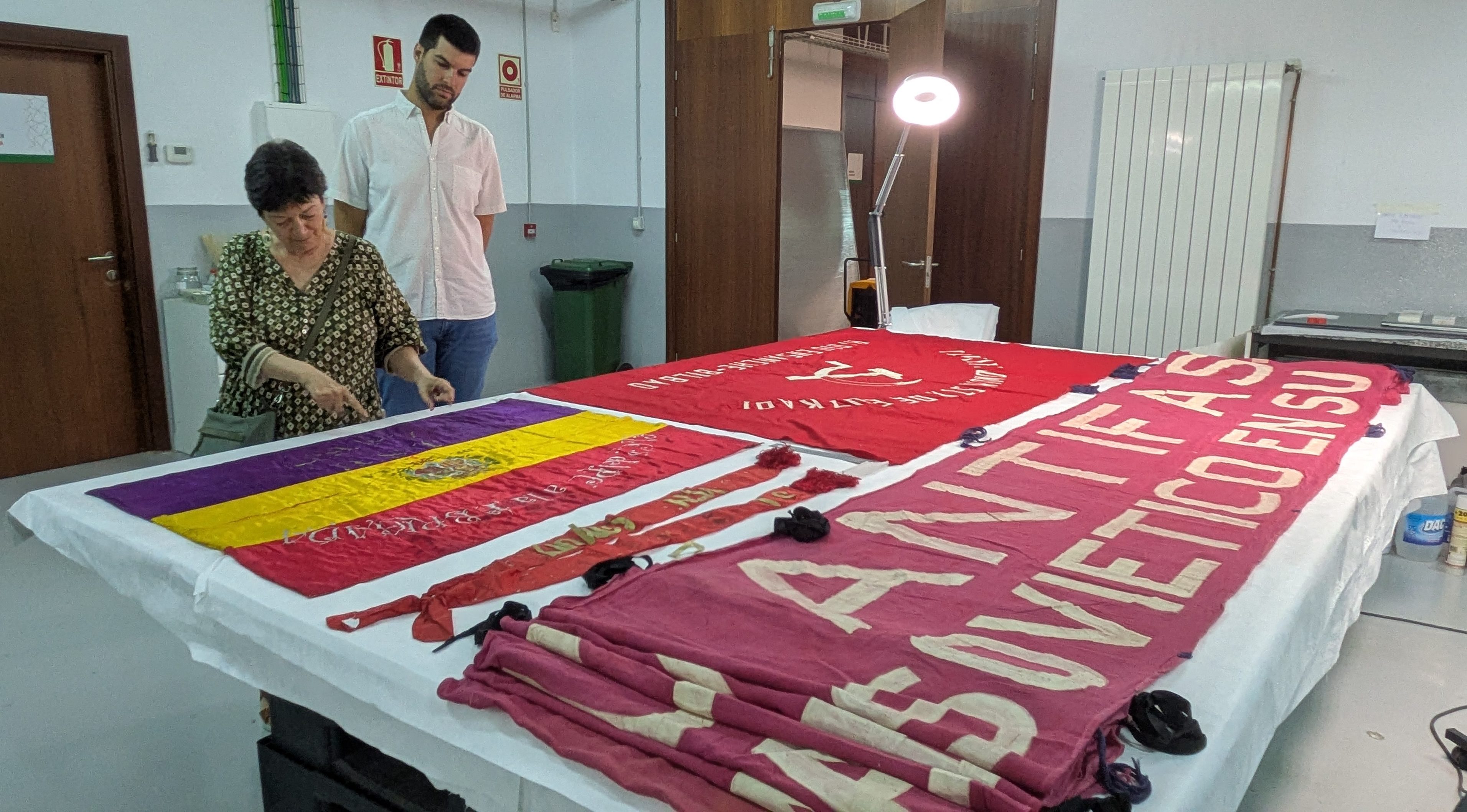 Isabel Burbano y Carlos Guzmán, contemplan las banderas del PCE depositadas en el Archivo General de Navarra.