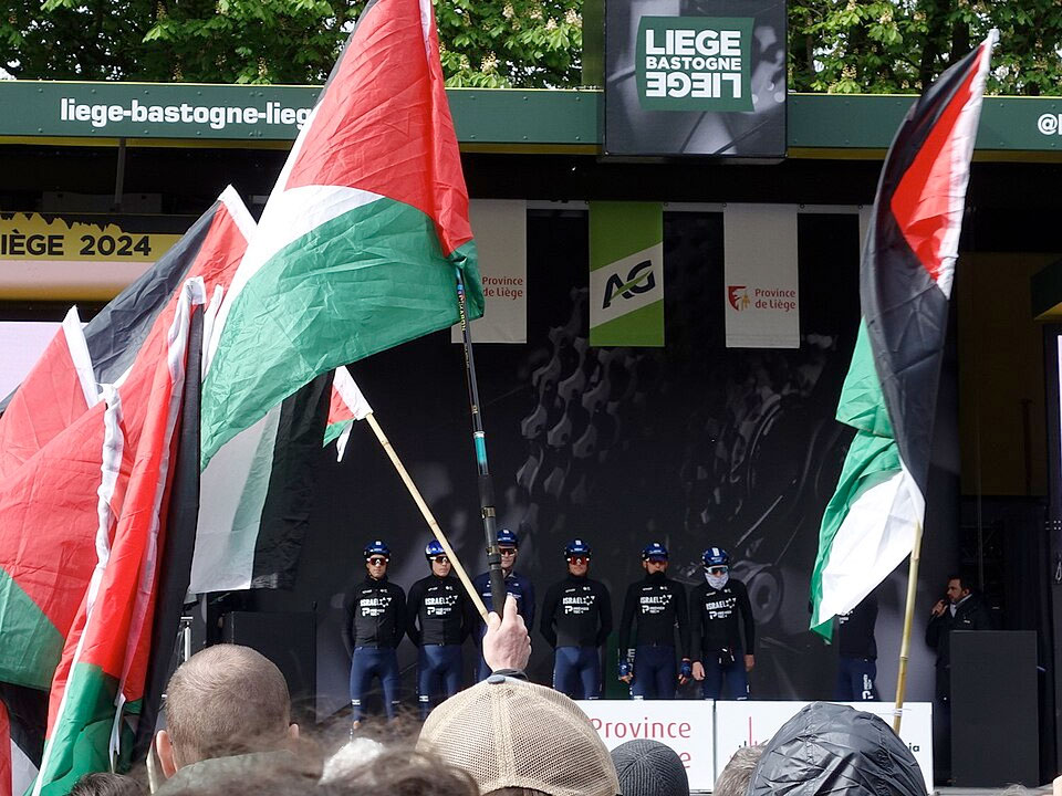 Banderas palestinas frente al equipo Israel-Premier Tech en la presentación de la clásica ciclista Lieja-Bastoña-Lieja (Bélgica), abril 2024 | Fuente: Hoebele / CC BY-SA 4.0