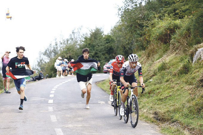 Jóvenes portando la bandera palestina protestan por la participación del equipo de Israel durante la etapa de la subida al Angliru (Asturias) en la Vuelta Ciclista a España 2025 | Fuente: @amantes_cycling